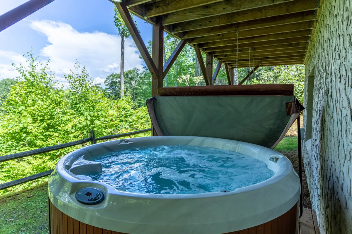 The image features a tranquil outdoor hot tub nestled among greenery, with space for several people to unwind together. The setting is ideal for socializing, relaxing, and enjoying the sights and sounds of nature—all key experiences for a family reunion or group retreat in the mountains.