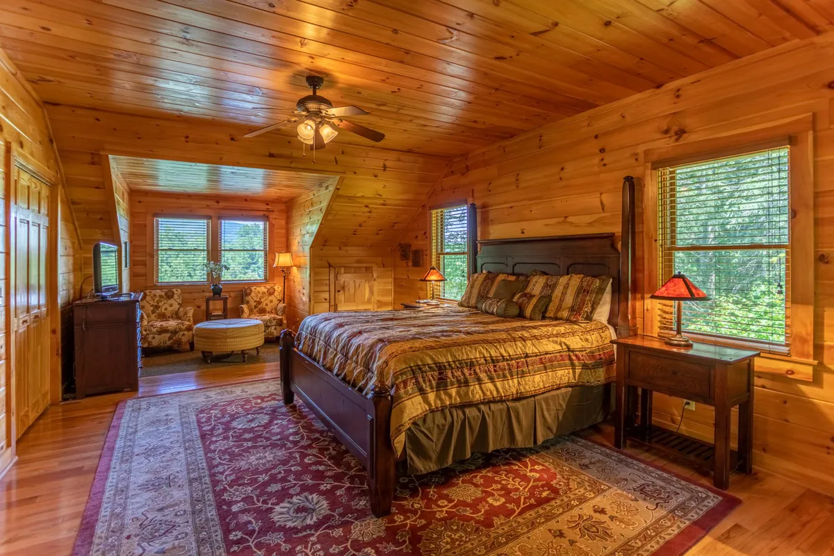 A serene king suite with a plush bed, comfy armchair by the window, soft area rug, and gentle lighting. The room exudes privacy and tranquility, offering a restful escape with views of the surrounding nature.