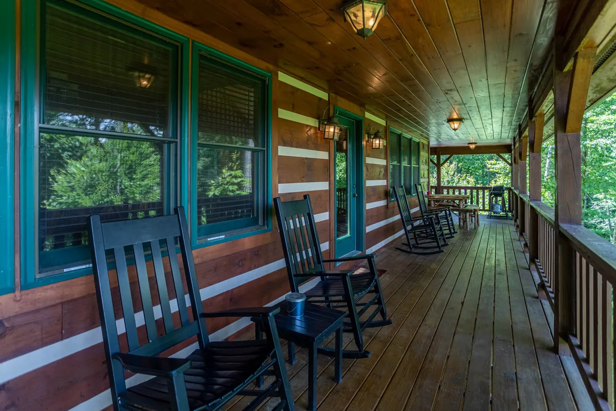 This exterior porch scene displays classic wooden rocking chairs positioned along the railing, with warm lighting fixtures and peaceful views into the surrounding landscape. The ambiance suggests quiet mornings or evenings spent talking, reading, or simply soaking in the mountain atmosphere as a group.